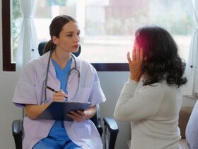 A doctor writing on a clipboard next to a person Description automatically generated