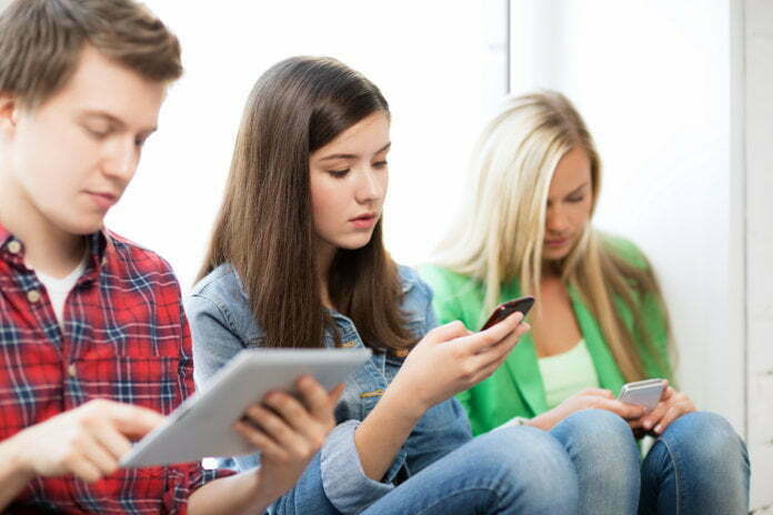 education concept - students looking into phones and tablet pc a