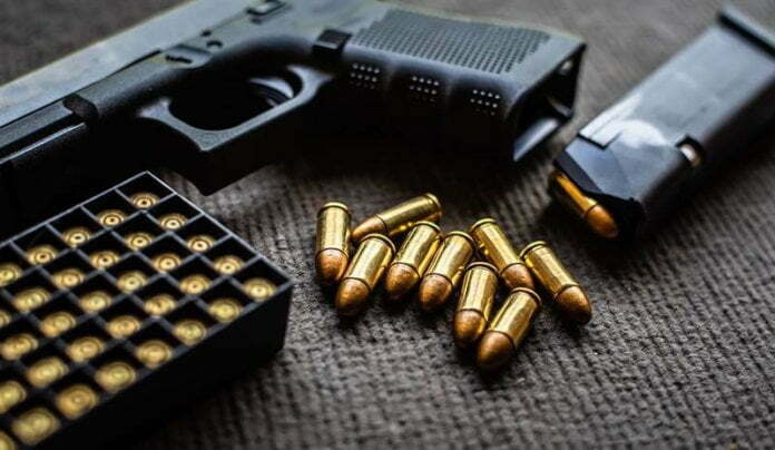 bullets and gun on black velvet desk