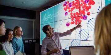 A person presenting to a group of people Description automatically generated with low confidence