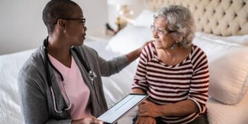 Two people sitting on a couch looking at a tablet Description automatically generated with low confidence