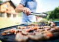 Unrecognizable man cooking seafood on a barbecue grill in the backyard on a sunny day.